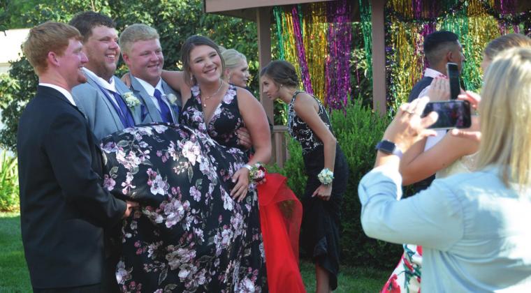 Senior classmates Jace Schaefer, Kyle Richardson and Tyler Ohlde hold Emily Myers for a candid photo for their parents after the prom walk.