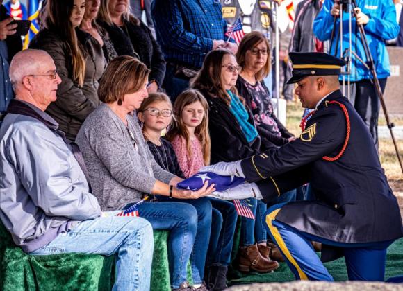 A flag is presented to Colleen Behrens, Marysville, a great-niece of Herynk. “To have it happen now is wonderful, but I think that it would have been better had one of the generations above us been here to see it, too,” said Behrens of the special ceremony. Photos by TOM PARKER